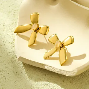 Details von goldenen Schleifenohrringen mit klarem Stein auf einem Keramiktablett