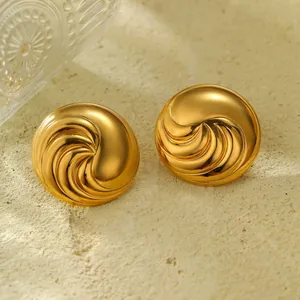 Nahaufnahme goldener Titanstahl-Ohrringe mit strukturierter Spirale und polierter Oberfläche