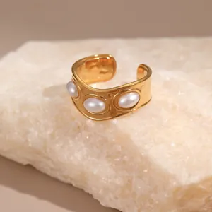 Detail eines 18K vergoldeten breiten Rings mit drei ovalen Perlen auf einer Steinplatte