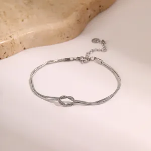 Macro detail van zilveren dubbele slangenketting armband met knoop en verstelbare karabijnsluiting