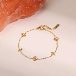 Macro detail of 18k gold plated clover charms with small diamonds on a fine link bracelet