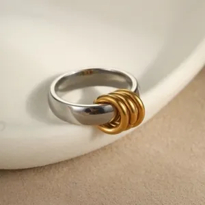 Makroaufnahme von poliertem Edelstahlring mit vier beweglichen vergoldeten Akzentringen