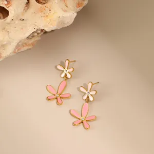 Detailweergave van roze emaille bloemenoorbellen met gouden afwerking en kleine strass
