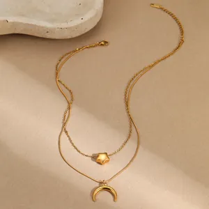 Detalle de collar multicapa de acero inoxidable con colgantes dorados de estrella y luna