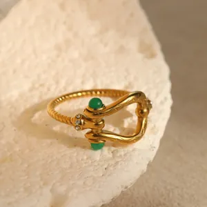 Makroaufnahme eines Vintage Hufeisenrings mit geflochtenem Band und grünen Steinen