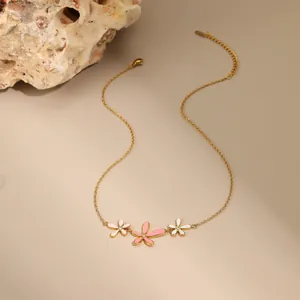 Detail van de gouden bloemenketting met roze en witte emaille bloemen en kristallen