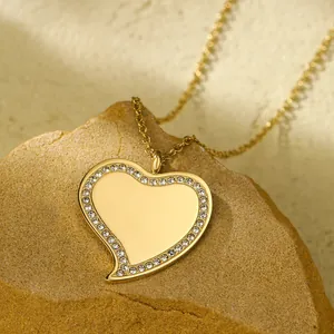 Dettaglio di una collana con ciondolo a cuore dorato e strass su una superficie di roccia