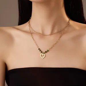 Detalle del collar de doble capa de oro de 18K con colgante de corazón y cuentas verdes