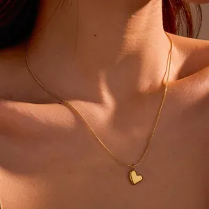 Primer plano de un collar con colgante de corazón dorado minimalista en cuello femenino