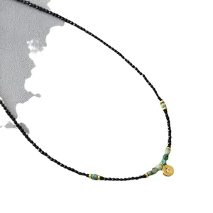 Beaded necklace featuring black spinel, turquoise accents and a gold starburst disc pendant