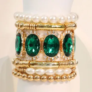 Retro palace style bracelet set with green gemstones, pearls and gold beads on a wrist