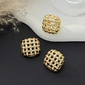Detailed macro view of three golden square braided stud earrings with high metal luster