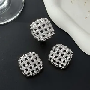 Macro detail of silver square stud earrings featuring intricate 3D woven texture design