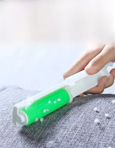Mini portable lint roller removing pet hair from grey fabric surface in close-up view