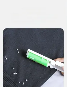 Close-up of portable lint roller removing pet hair and dust from black knit fabric