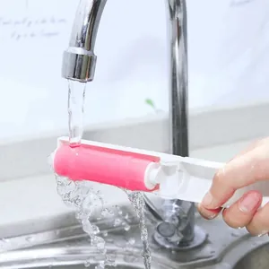 Portable pink washable lint roller for pet hair removal being cleaned under a faucet