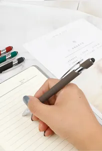 Close-up of a premium metal ballpoint pen being used on a notebook in a lifestyle setting