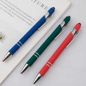Three premium metal touch ballpoint pens in blue, green and red on minimalist white desk