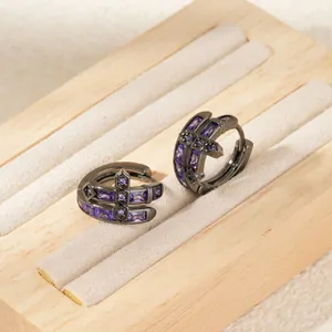 Détail de boucles d'oreilles gothiques avec pierres zircons mauves et croix noire