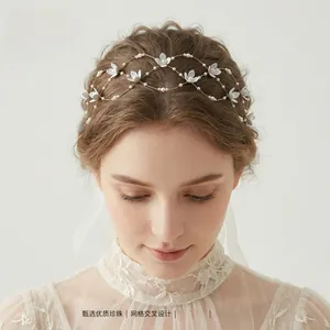 Détail d'un serre-tête de mariée artisanal avec fleurs blanches et maille dorée