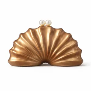 Détail de la pochette coquillage dorée avec textures ondulées et fermoir à perles