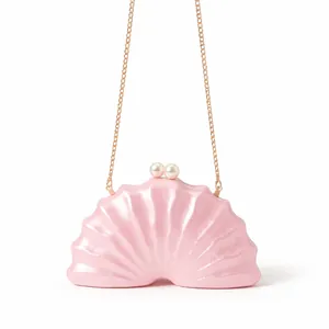 Détail du sac de soirée en nacre rose avec fermoir perle et chaîne dorée