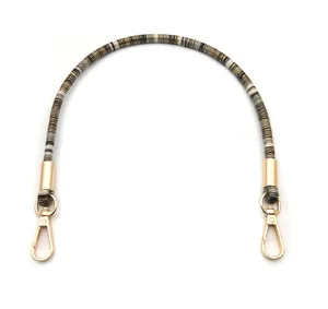 Close-up of ethnic style replacement purse strap with multi-color beads and gold metal clasps