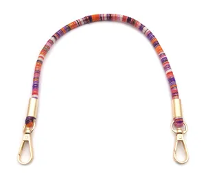 Close-up of a colorful woven bag strap featuring vibrant stripes and gold metal hooks