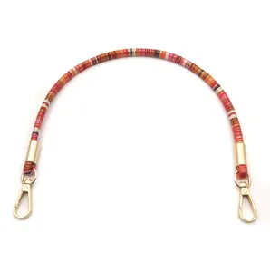 Detail of colorful woven braided handbag handle strap with gold-tone lobster clasps