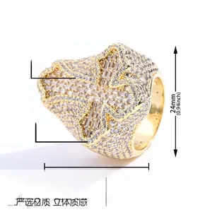 Dettaglio dell'anello a croce hip hop in ottone dorato con zirconi bianchi brillanti