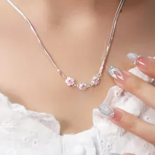 Detail of silver chain necklace with three pink cherry blossom pendants on a neck