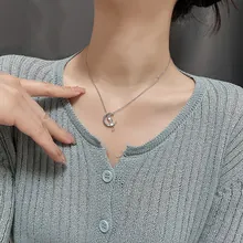 Close-up of crescent moon pendant necklace with white pearl on model neck