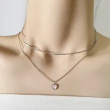 Close-up of double-layered silver feather necklace with heart pendant on model