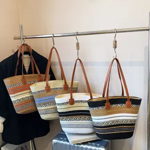 Detail view of woven tote bags in various patterns with brown faux leather shoulder straps