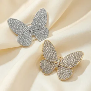 Elegant gold and silver butterfly brooches with shimmering rhinestones on silk fabric