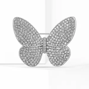 Detailed close-up of sparkling rhinestone butterfly brooch on elegant white geometric blocks