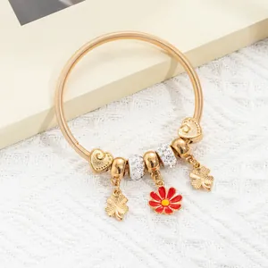 Golden spring charm bracelet with red daisy and clover pendants on lace background