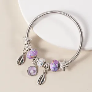 Detailed macro view of ocean themed silver charm bracelet with purple shells and starfish