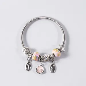 Silver spring bracelet featuring seashell charms, starfish pendant, and beads on grey surface