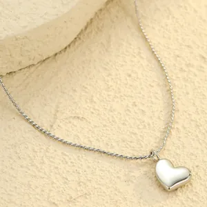 Primer plano de un colgante de corazón pulido espejo con cadena de cuerda fina de acero