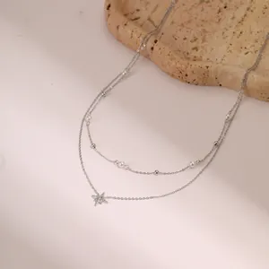 Detalle de collar estrella plateado de doble capa con micropavé y perlas de imitación