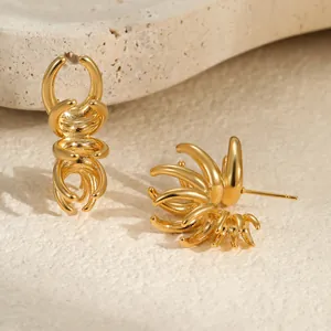 Détail de boucles d'oreilles griffes dorées montrant des lignes courbes et tiges en métal