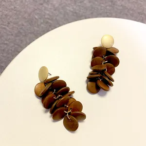 Detail of vintage wooden long tassel earrings with geometric brown circular discs