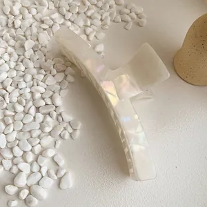 Elegant large pearlescent white acetate hair claw clip for women on a stone background