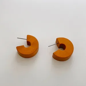 Dettaglio degli orecchini in legno a forma di C con trama e perni in argento lucido