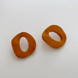 Dettaglio orecchini geometrici in legno a forma di C con trama naturale marrone arancio