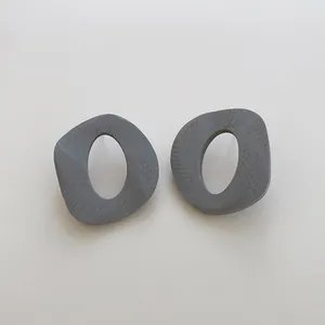 Vista macro degli orecchini geometrici a C con una finitura a venature di legno grigio scuro