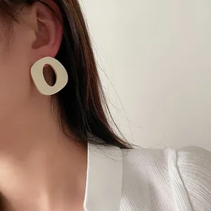 Orecchini a cerchio a C geometrici color crema minimalisti indossati da una modella