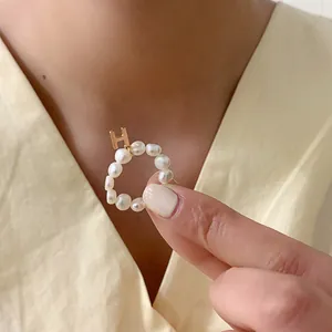 Detailopname van een parelring met een hangende gouden letter H bedel voor dames