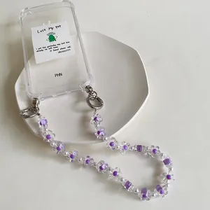 Dettaglio custodia trasparente con perline a fiore viola e cinturino di perle